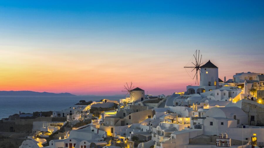 Cycladic sunset village with white houses and windmills overlooking the Aegean Sea.