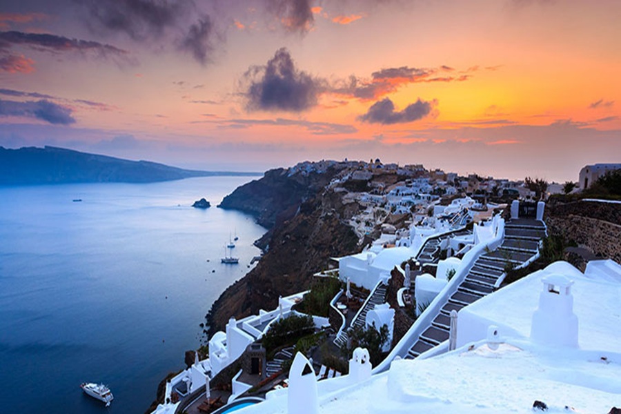 Santorini sunset over Aegean Sea and whitewashed buildings with colorful sky.