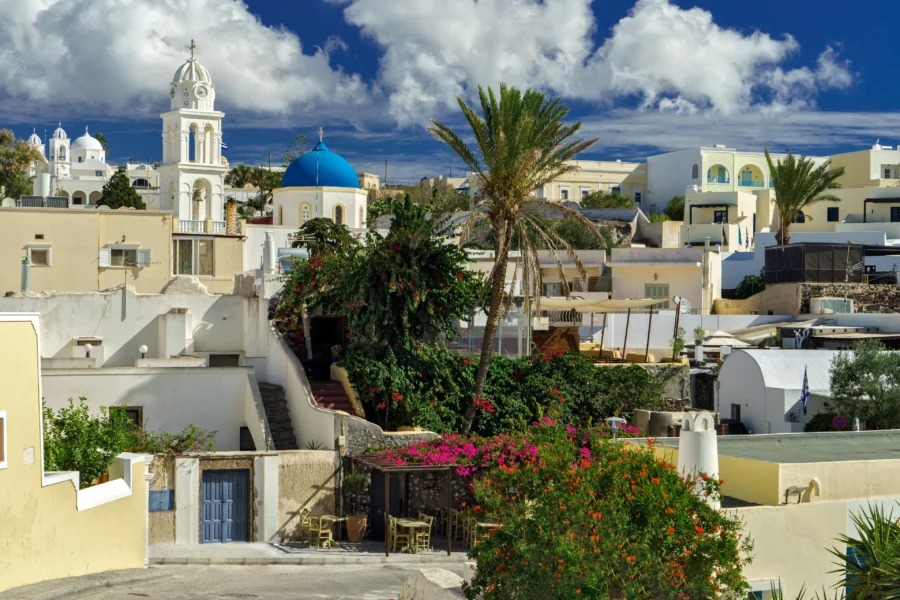 Stunning Greek island village with white buildings, windmill, and blue sea views.