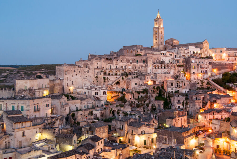 Sassi di Matera illuminated at dusk, showcasing ancient stone buildings against a twilight sky in Basilicata, Italy.