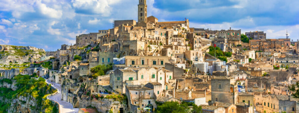Panoramic view of Sassi di Matera, showcasing ancient cave dwellings and rocky cliffs under a clear blue sky.
