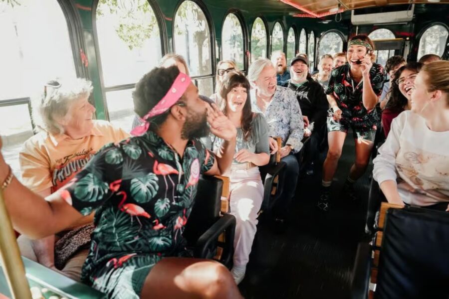 Passengers on a trolley bus, including a person wearing a floral shirt, as part of the Savannah For Morons Guided Comedy Tour.