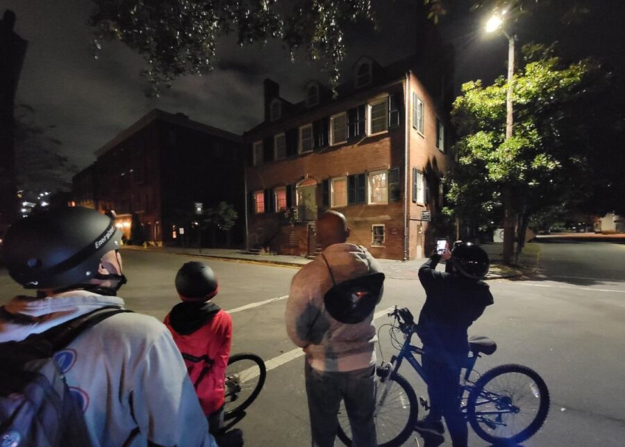 Participants on bikes photograph a building while enjoying the Savannah Haunted Night Bike Tour.