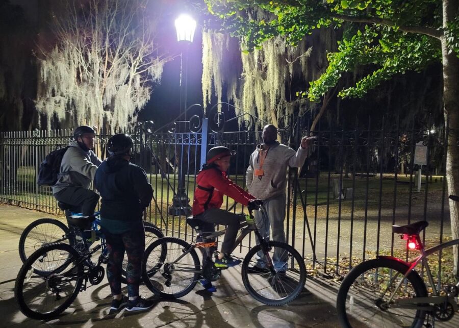 Participants stand around their bikes at night, ready for the Savannah Haunted Night Bike Tour adventure.