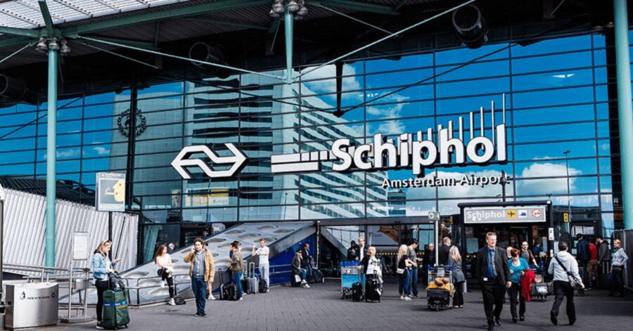 Schiphol Airport entrance showcasing modern architecture, travelers, and Dutch railway connectivity.