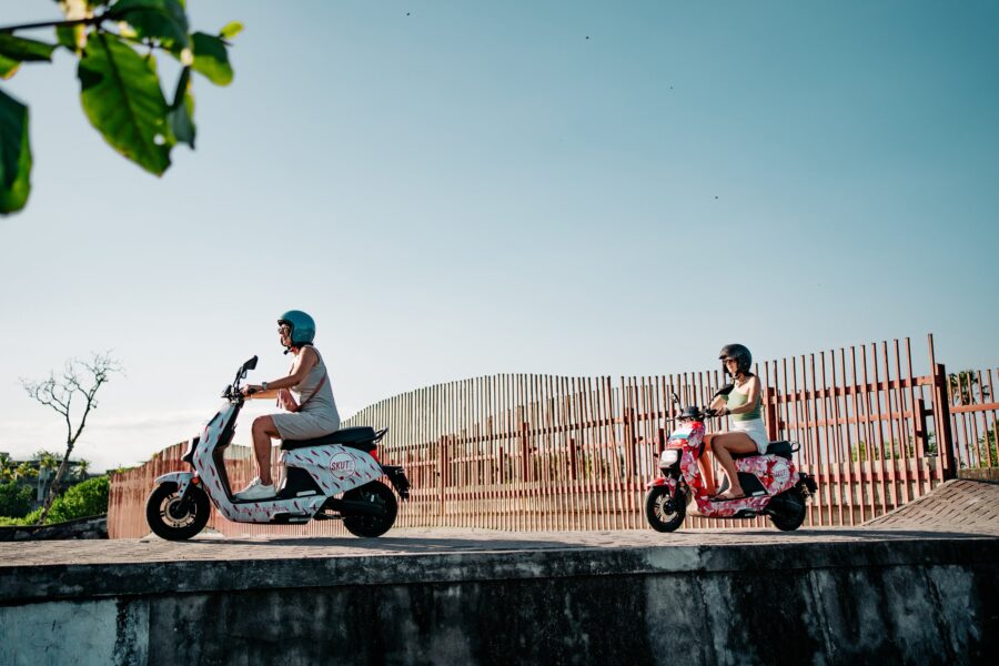Two friends enjoy electric scooters outdoors amid nature and modern design.