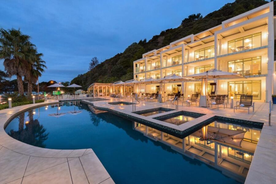 Luxury seaside resort and spa with illuminated infinity pool at dusk in Paihia, New Zealand.