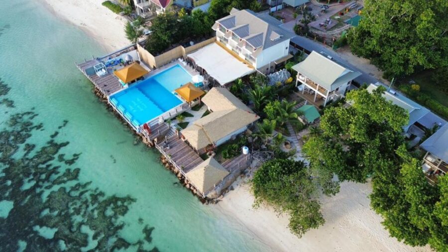 Aerial view of La Digue luxury beachfront resort with infinity pool, white sand and turquoise lagoon.