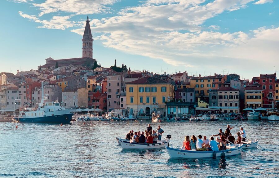 Vibrant coastal town with colorful boats, historic architecture, and lush hills.