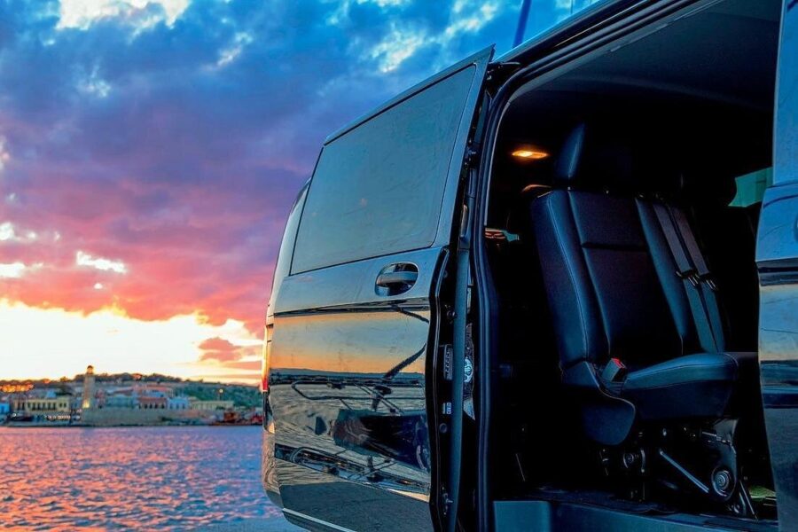 Seaside private transfer van at sunset with open sliding door and leather seats.