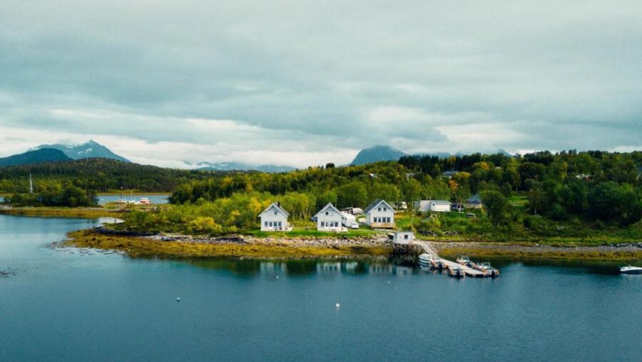 The Senja Arctic Lodge overlooks a tranquil lake, with a quaint small town nestled along the shore.
