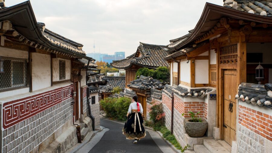 Asian woman in hanbok walking through historic Bukchon Hanok Village, Seoul, Korea.