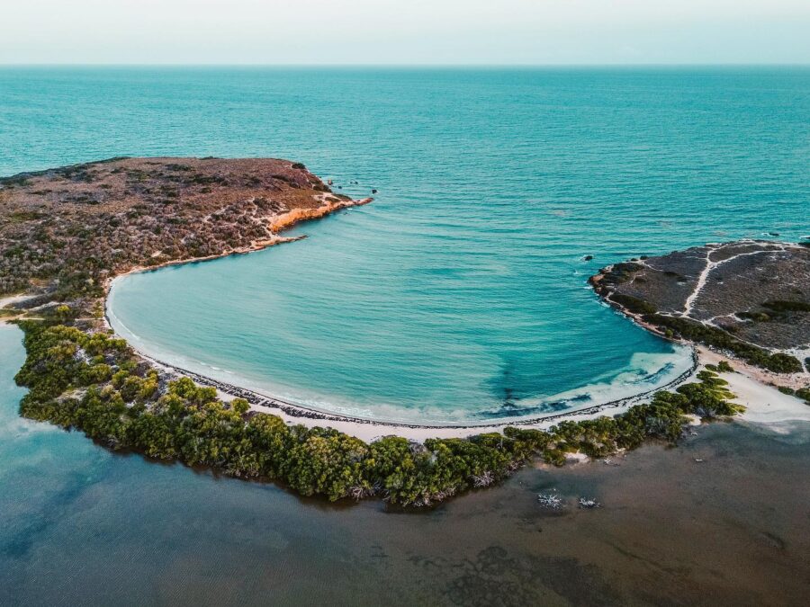 Aerial view of Playa Sucia bay with turquoise water, white sand beach and rugged coastline.