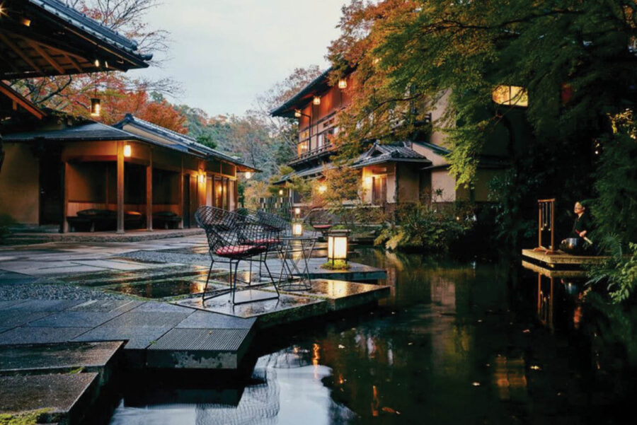 Serene Japanese courtyard with traditional architecture, lush gardens, and a tranquil pond at dusk.