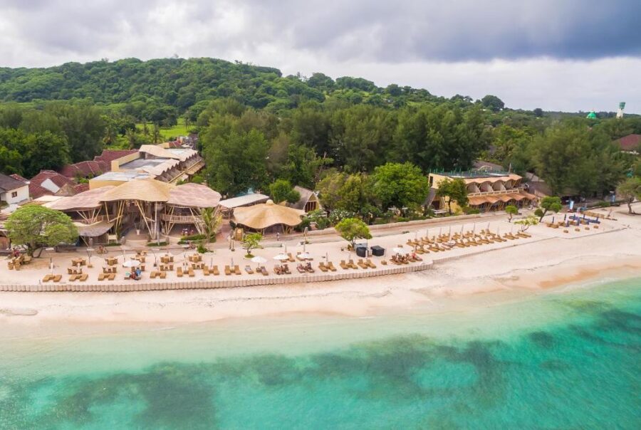 Aerial view of tropical beachfront resort with white sand, turquoise water and luxury sun loungers.