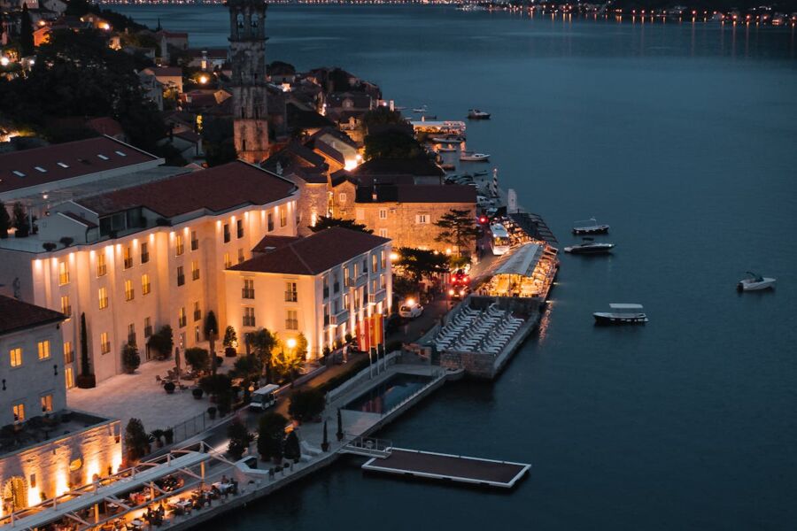 Coastal town night scene with marina, illuminated buildings, and vibrant waterfront ambiance.