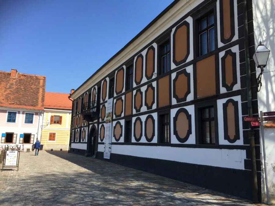 Sermage Palace in Varaždin, Croatia, features a striking white and black facade with numerous windows.
