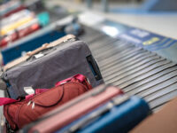 Various suitcases and bags travel on a conveyor belt in an airport, ready for passenger pickup