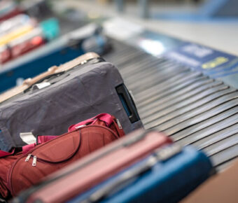 Various suitcases and bags travel on a conveyor belt in an airport, ready for passenger pickup