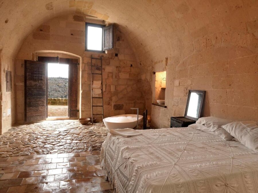 Cozy bedroom featuring rustic stone walls and a stone floor, located in Sextantio Le Grotte Della Civita.