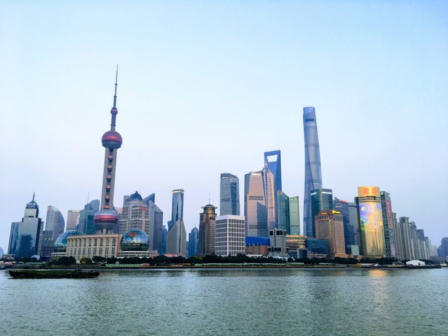 Pudong skyline at twilight with Oriental Pearl Tower and Huangpu River reflecting city lights.