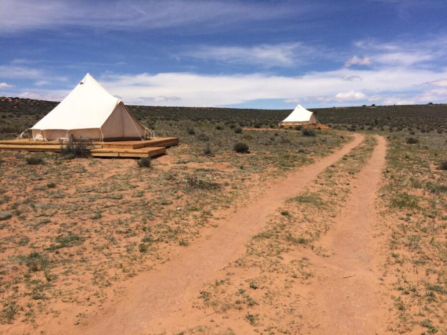 Shash Dine EcoRetreat, two tents are set up along a dirt road, blending with the surrounding landscape.
