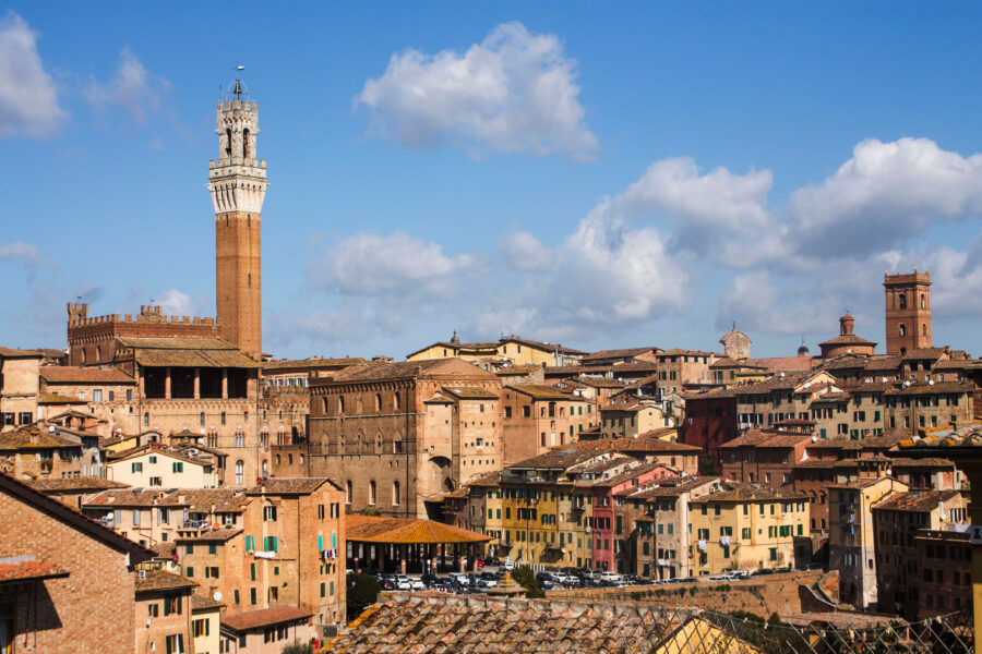 Panoramic view of Siena, showcasing its historic architecture and rolling hills of Tuscany under a clear blue sky