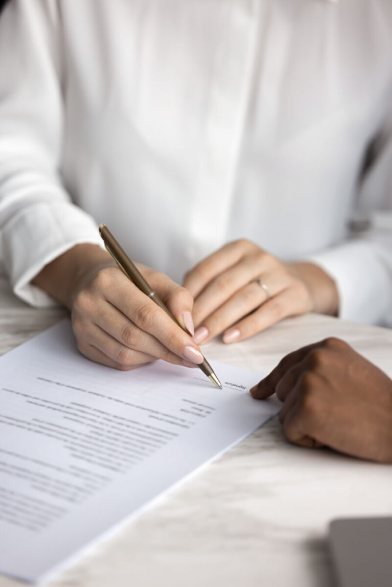 Individual signing and filing a document at a desk, focused on completing the paperwork.