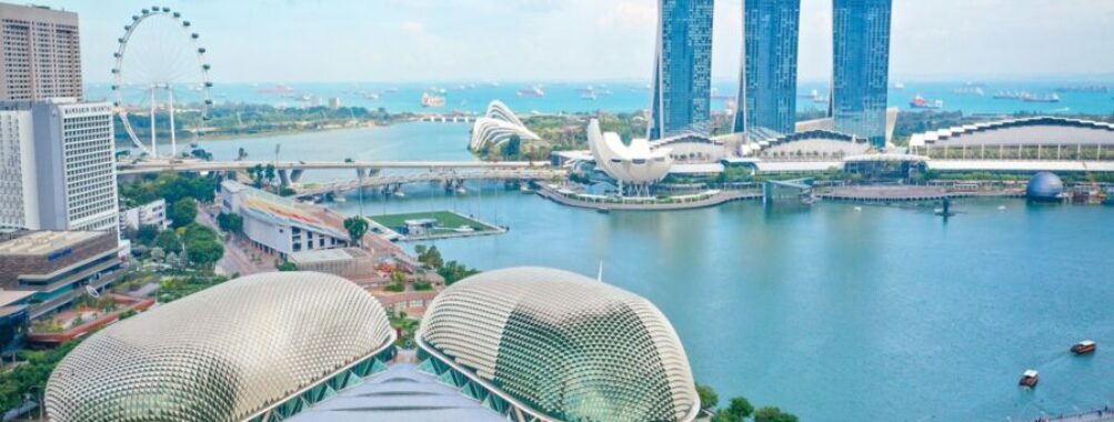 Aerial view of iconic Singapore skyline, Marina Bay Sands, Esplanade, and lush greenery.