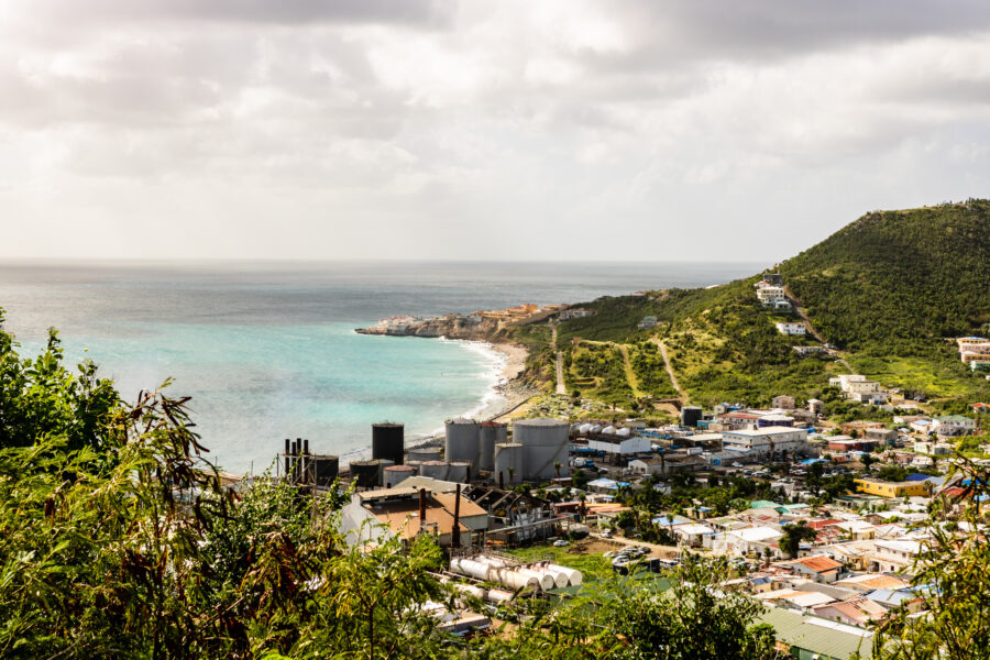 Panoramic view of St Martin/Sint Maarten island from a mountain, showcasing the Caribbean Sea and lush landscapes.