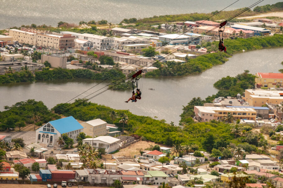 Person zip lining from the steepest zip line in the world, enjoying panoramic views of Saint Maarten's lush scenery