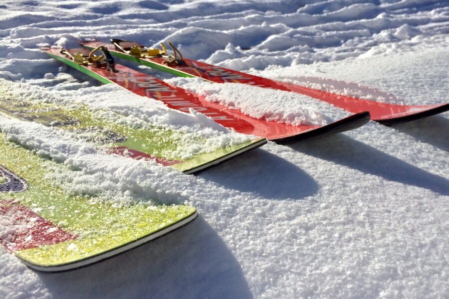 Colorful skis resting on fresh snowy slopes under bright sunlight.