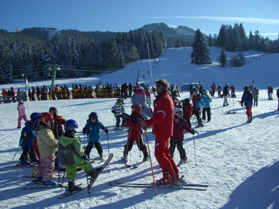 Childrens ski lesson at sunny resort with energetic instructor and picturesque snowy landscape.