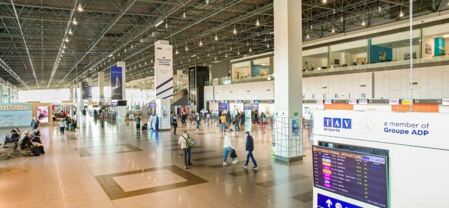 Interior view of Skopje International Airport, featuring travelers walking through the terminal.