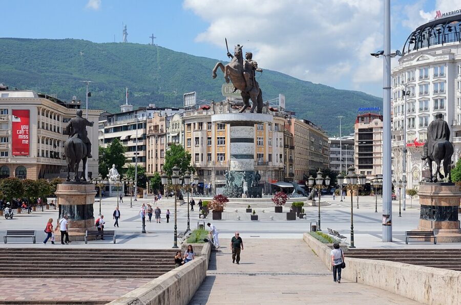 Skopje's city square filled with statues and pedestrians enjoying the vibrant atmosphere.