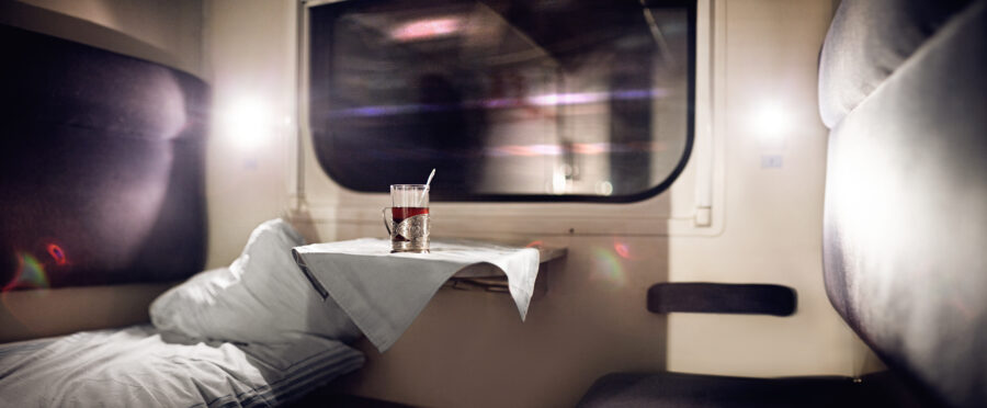 Vacant sleeper train compartment with two bunks, a window, and simple decor, showcasing a cozy travel space.