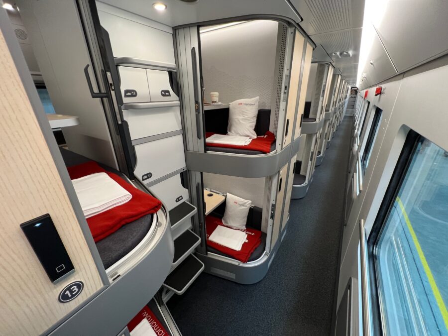 ÖBB Nightjet sleeper train interior with modern two-tier sleeping pods and aisle.