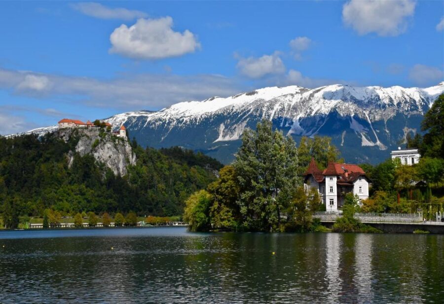Scenic view of Lake Bled, Slovenia, featuring the Adora Luxury Hotel amidst lush greenery and tranquil waters.