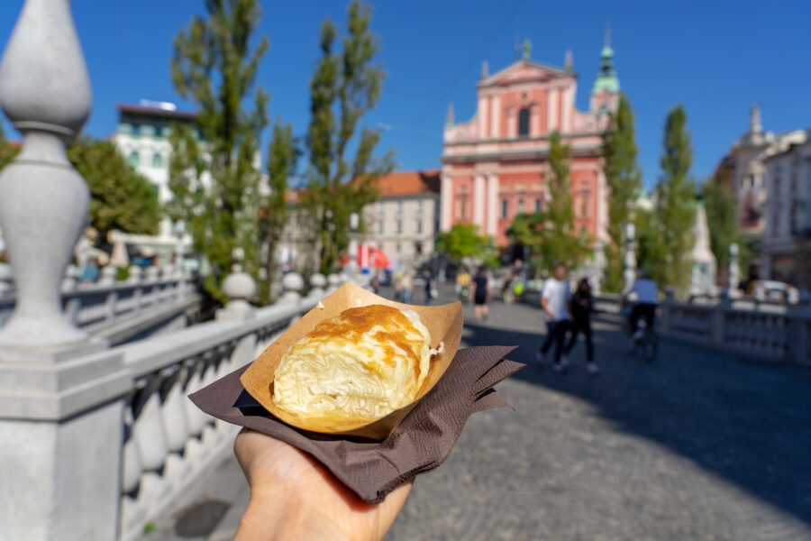 Enjoying a traditional Slovenian strukelj roll in a picturesque setting in Ljubljana