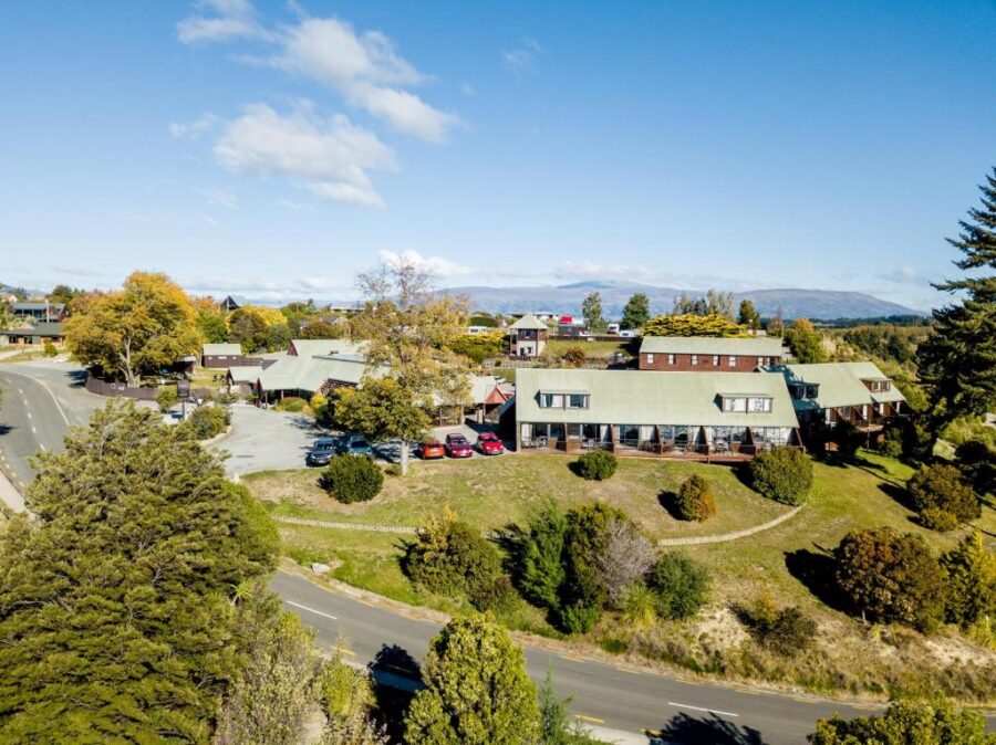 Aerial view of Hawea Hotel lodge in small town New Zealand countryside with mountains.