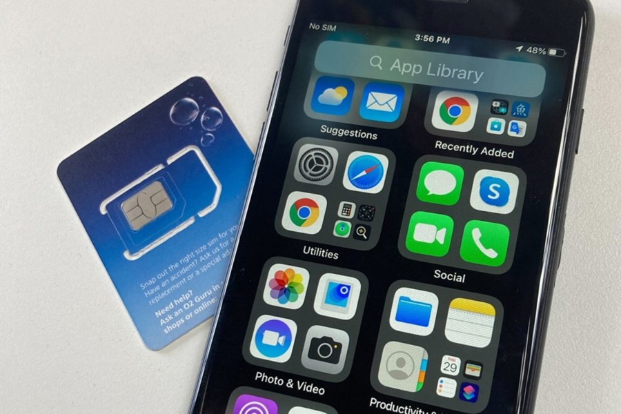 Smartphone with apps and SIM card from O2 displayed on light surface.