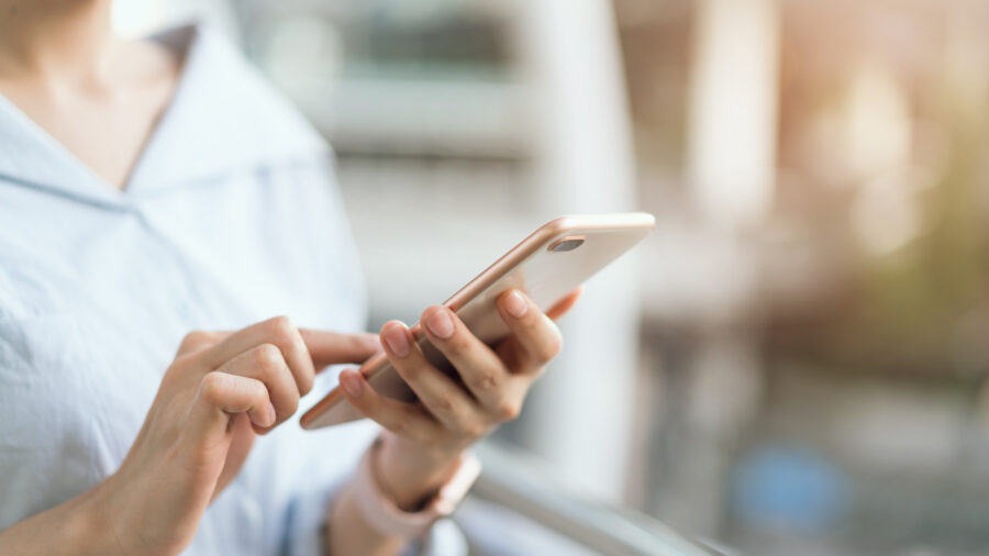 Woman using a smartphone while sitting on a staircase in a public area during her leisure time.