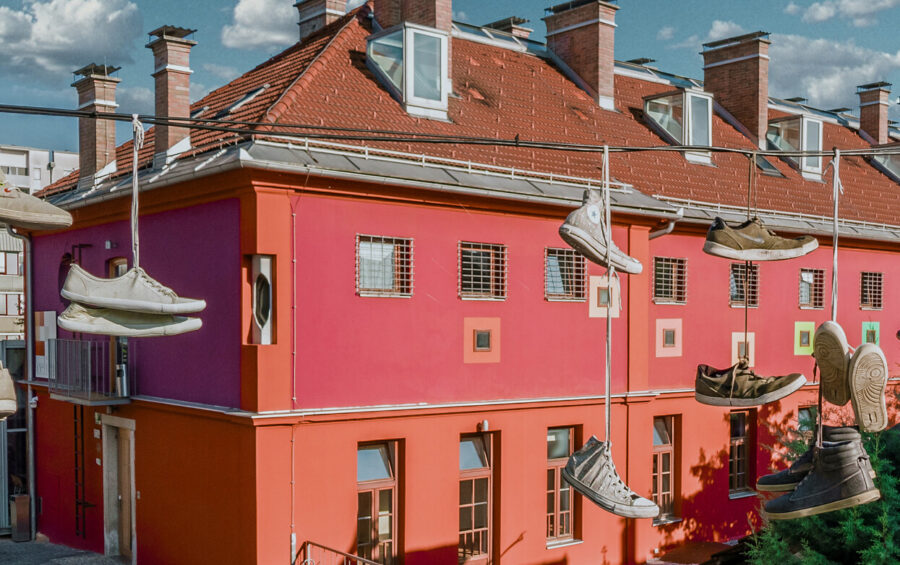 Sneakers and shoes hanging on wires over colorful Hostel Celica courtyard.