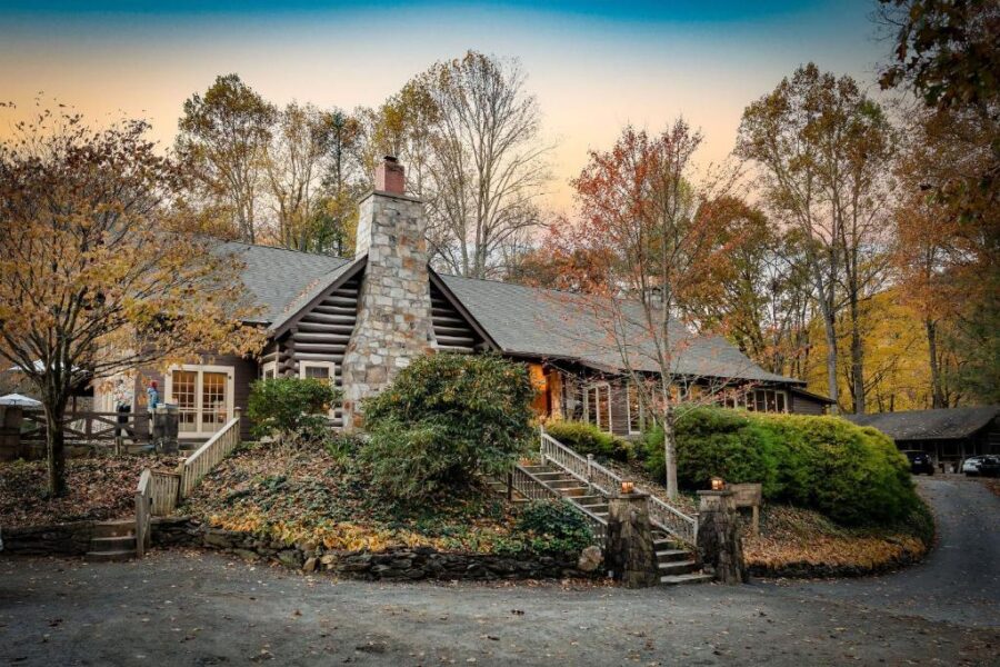 Snowbird Mountain Lodge in North Carolina, showcasing a log cabin encircled by trees and a charming stone walkway.