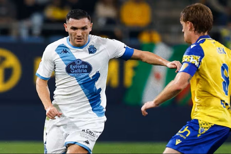 Cádiz vs A Coruña soccer clash: white-blue sash captain battles yellow number 8.