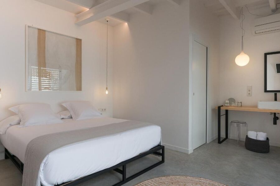 Interior of a bedroom at Sodium Boutique Hotel in Menorca, showcasing white walls and a comfortable bed.