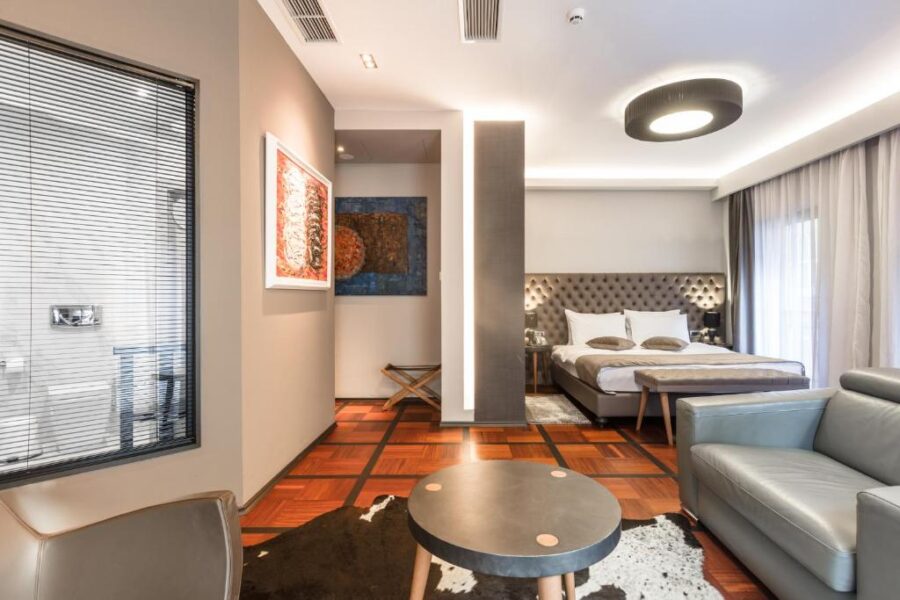 Modern hotel room at Solun Hotel & SPA in Skopje, featuring a bed, couch, and television.