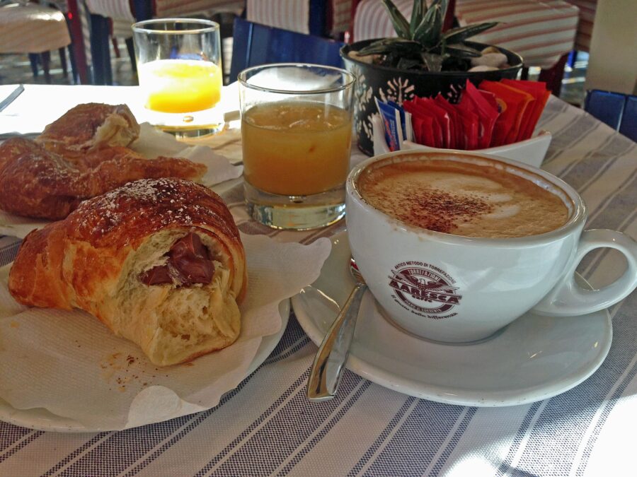 Croissant and a cup of coffee on a table, representing a Sorrento breakfast with macchiato.