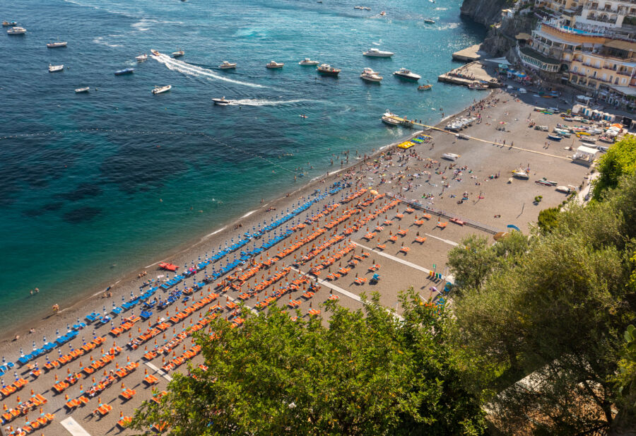 Spiaggia Grande beach in Positano, showcasing bright orange and blue umbrellas with the stunning blue sea of the Amalfi Coast.