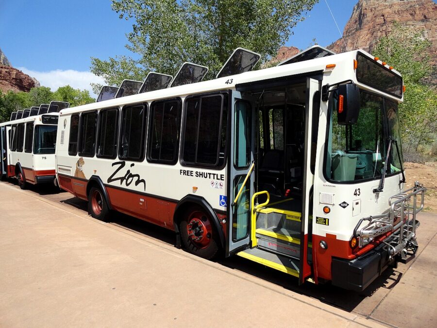 Two buses parked along a road in Springdale, Utah, serving the Zion National Park shuttle service.
